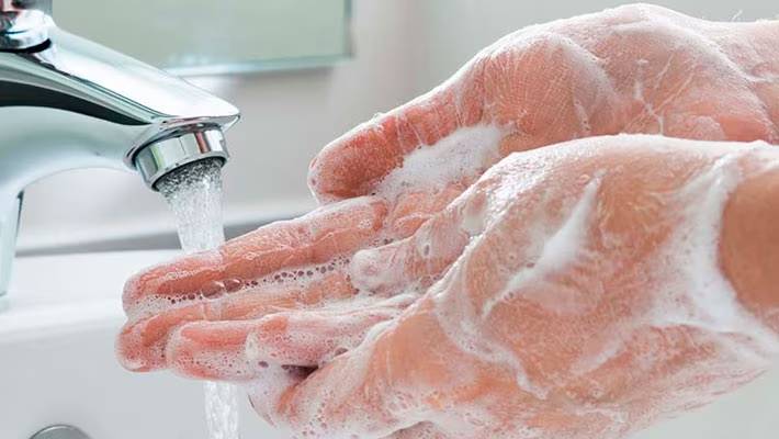 Close-up van ingezeepte handen die worden afgespoeld onder stromend water uit een chromen kraan.